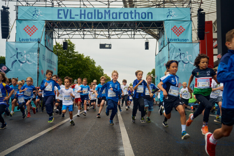 Kinder beim EVL-Halbmarathon in Leverkusen, die auf der Straße laufen.