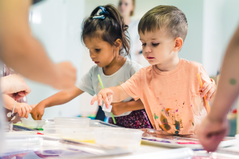 Kinder beim Malen in einer kreativen Umgebung mit Farben und Materialien.